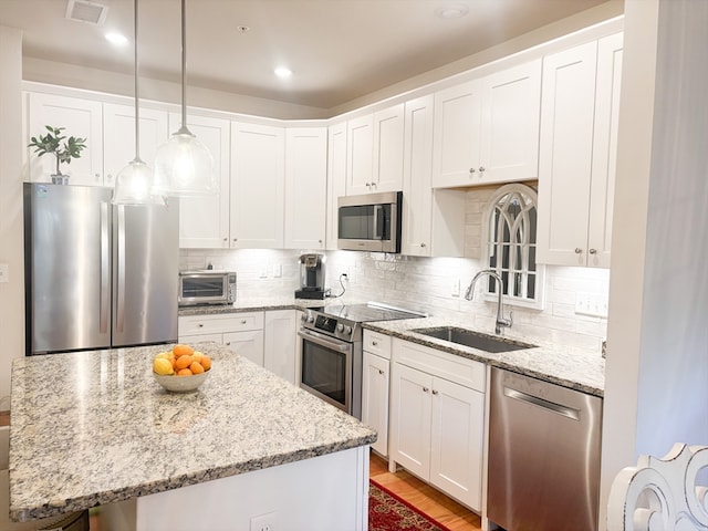 kitchen with stainless steel appliances, sink, hanging light fixtures, a center island, and white cabinets