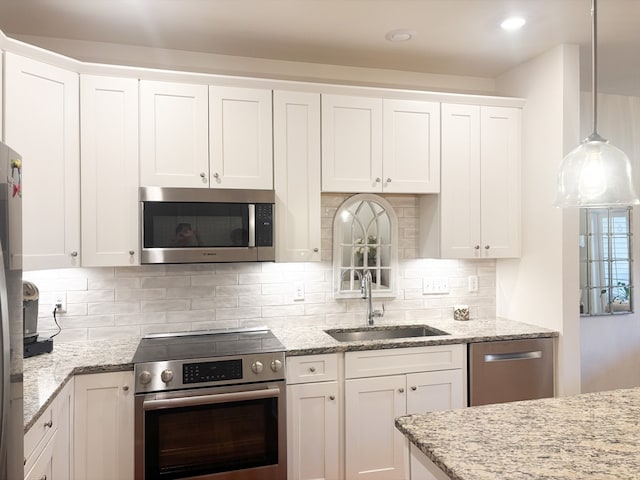 kitchen featuring light stone counters, stainless steel appliances, white cabinetry, backsplash, and decorative light fixtures