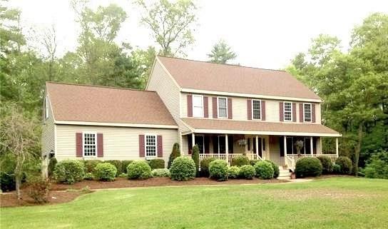 colonial-style house featuring covered porch and a front yard