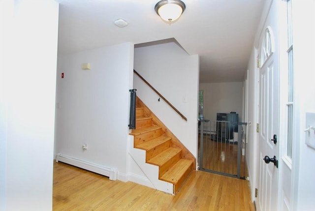 stairs with a baseboard radiator and wood finished floors