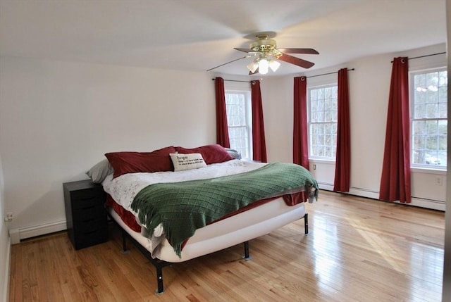 bedroom featuring baseboard heating, light wood-type flooring, and a ceiling fan