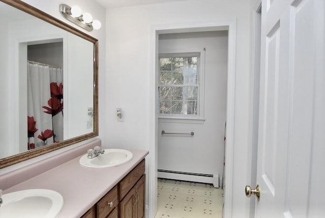 full bath with a sink, a baseboard heating unit, and double vanity