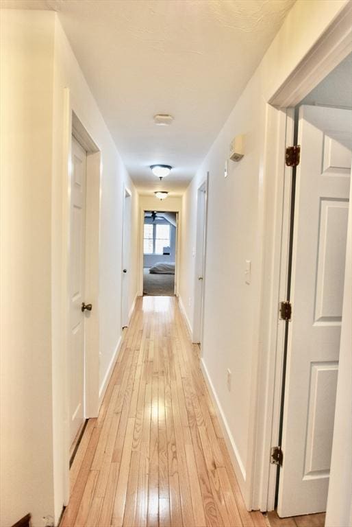 hallway featuring light wood-type flooring and baseboards