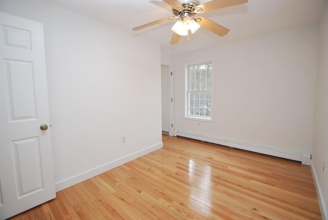 spare room featuring baseboard heating, a ceiling fan, baseboards, and wood finished floors