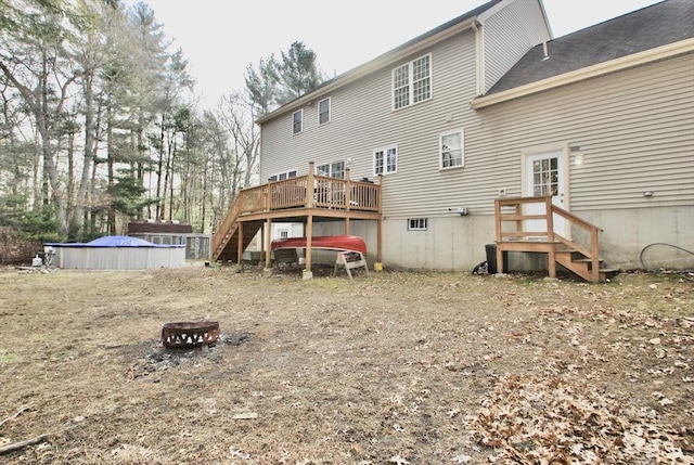 rear view of house featuring a wooden deck and a fire pit