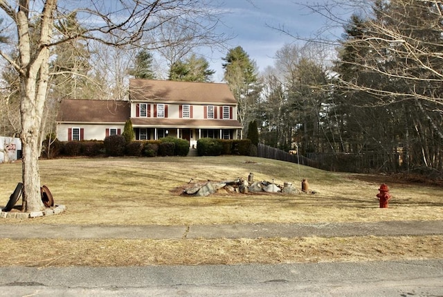 colonial-style house featuring a front lawn and fence