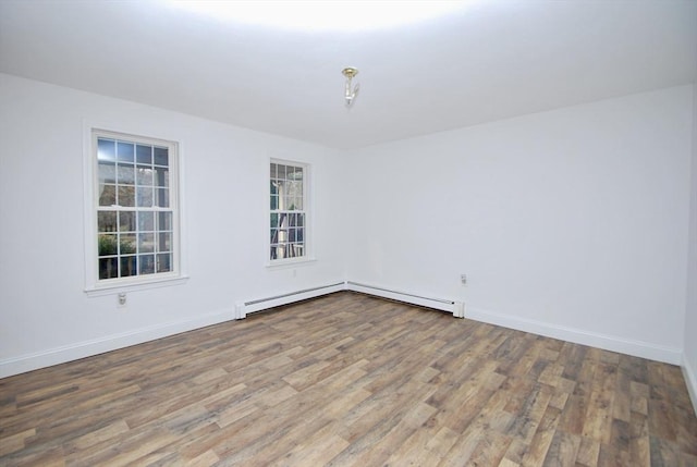 spare room with wood finished floors, baseboards, and baseboard heating