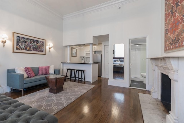 living area featuring a fireplace with flush hearth, dark wood-style flooring, crown molding, and a towering ceiling