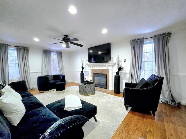 living room featuring a tile fireplace, a wealth of natural light, hardwood / wood-style floors, and ornamental molding