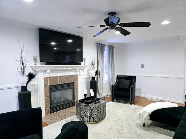 bedroom with crown molding, ceiling fan, a tile fireplace, and light hardwood / wood-style flooring