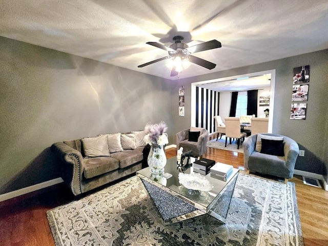 living room featuring hardwood / wood-style flooring, a textured ceiling, and ceiling fan