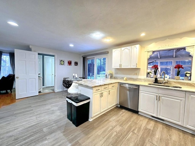 kitchen featuring sink, white cabinets, stainless steel dishwasher, kitchen peninsula, and light hardwood / wood-style flooring