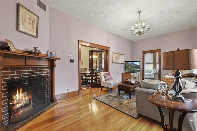97 Livingston Ave, Lowell, MA 01851 - living room featuring visible vents, light wood-type flooring, an inviting chandelier, and a brick fireplace