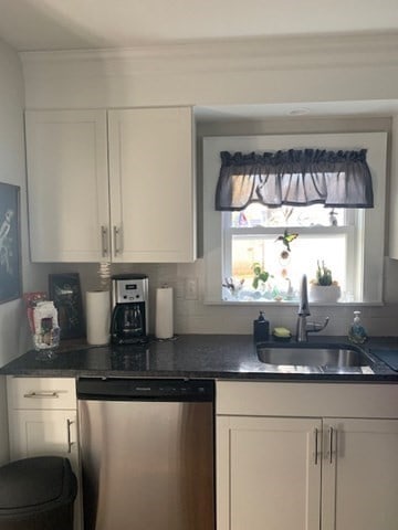 kitchen featuring decorative backsplash, white cabinets, stainless steel dishwasher, ornamental molding, and sink