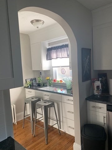 kitchen featuring white cabinets, radiator, and wood-type flooring