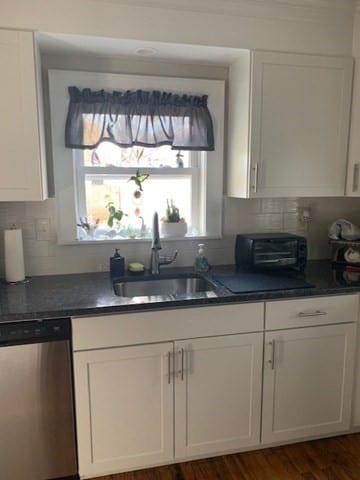 kitchen featuring dishwasher, sink, dark hardwood / wood-style flooring, white cabinetry, and tasteful backsplash