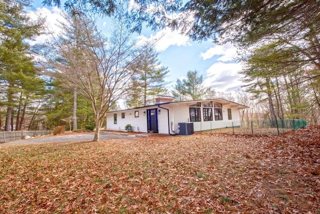 rear view of house with central AC, a chimney, and fence