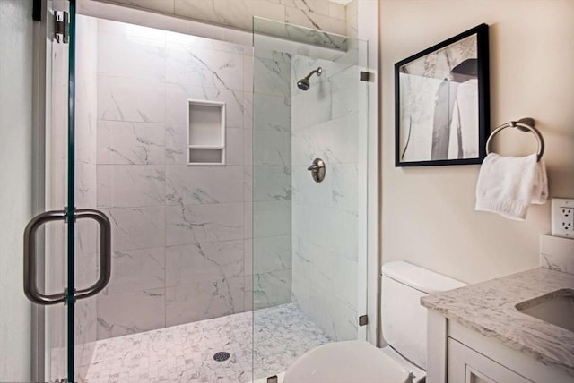 full bathroom featuring toilet, a shower stall, and vanity