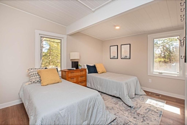 bedroom featuring beamed ceiling, multiple windows, visible vents, and baseboards