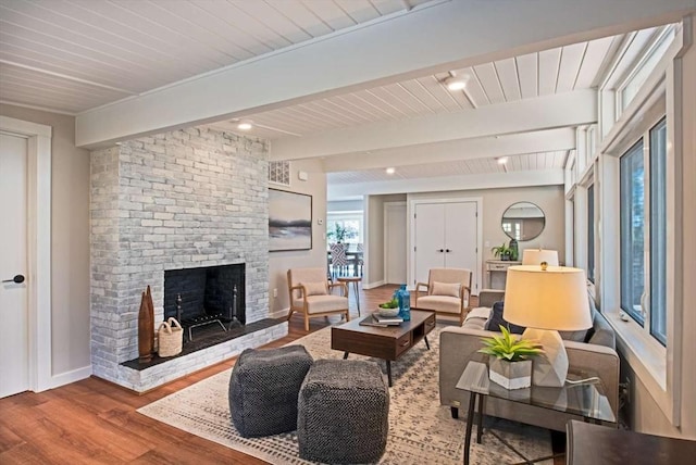 living area with a fireplace, wood finished floors, beam ceiling, and baseboards