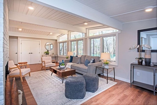 living area with baseboards, wooden ceiling, vaulted ceiling with beams, light wood-type flooring, and a fireplace