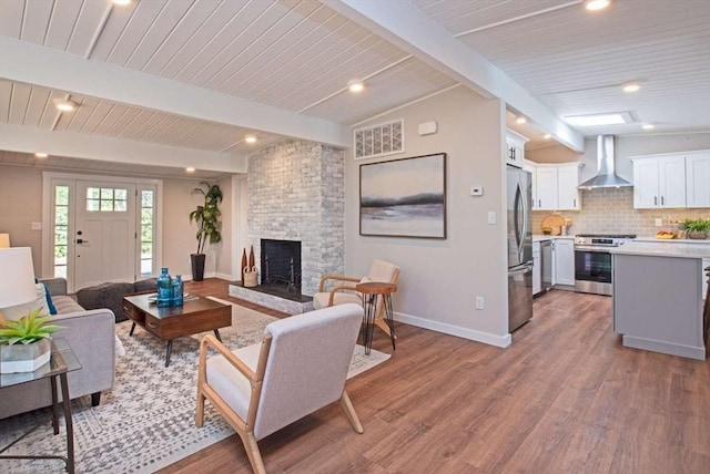 living room featuring light wood finished floors, visible vents, a fireplace, and baseboards