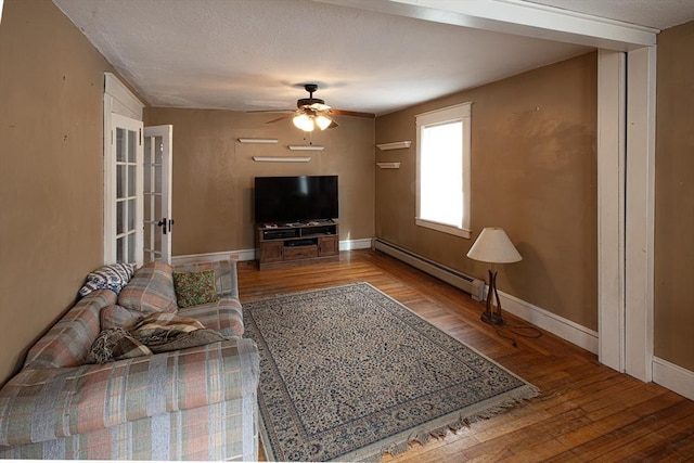 living room featuring ceiling fan, baseboards, baseboard heating, and hardwood / wood-style floors