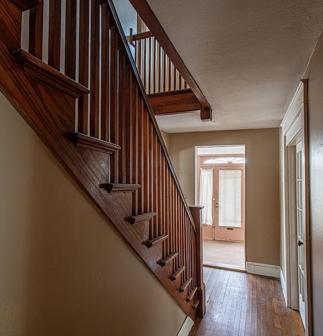 stairs featuring baseboards, a textured ceiling, and hardwood / wood-style floors