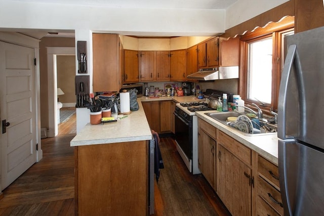 kitchen with range with gas cooktop, freestanding refrigerator, light countertops, under cabinet range hood, and a sink