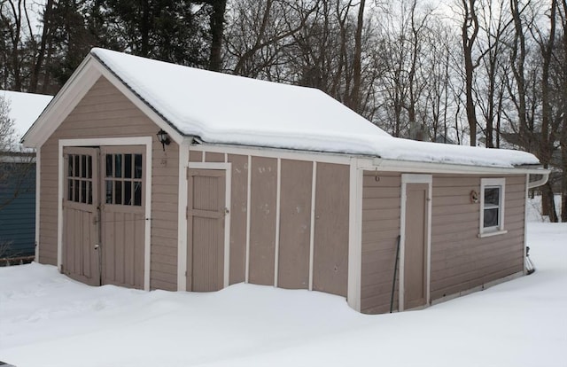 snow covered structure featuring an outbuilding