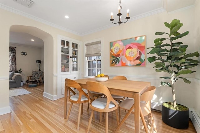 dining room with visible vents, ornamental molding, arched walkways, light wood-style floors, and baseboard heating