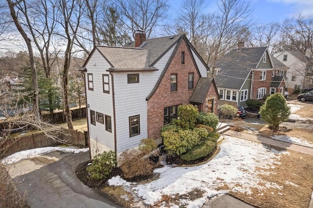 view of property exterior with fence, brick siding, roof with shingles, and a chimney