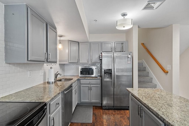 kitchen with light stone countertops, hanging light fixtures, dark hardwood / wood-style floors, backsplash, and appliances with stainless steel finishes