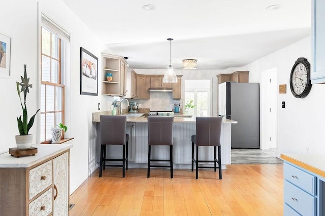 kitchen featuring freestanding refrigerator, a peninsula, open shelves, and a wealth of natural light
