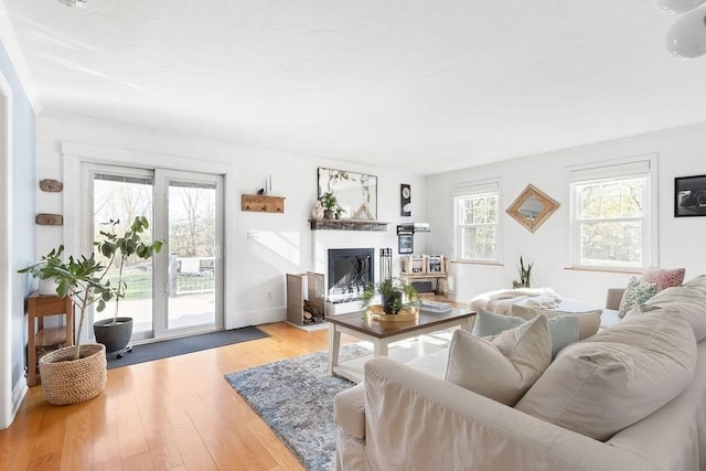 living area with baseboards, a glass covered fireplace, and wood finished floors