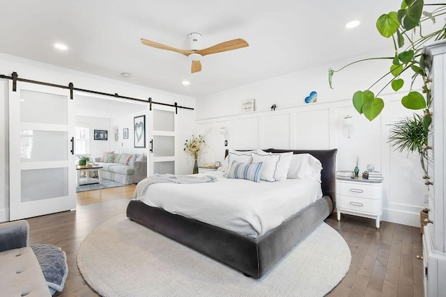 bedroom featuring a ceiling fan, recessed lighting, a barn door, and dark wood-type flooring