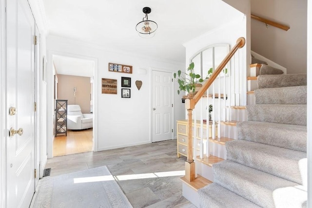 foyer entrance featuring ornamental molding, stairs, and visible vents