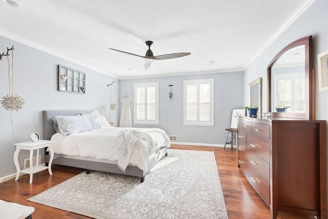 bedroom featuring crown molding, visible vents, wood finished floors, baseboards, and ceiling fan