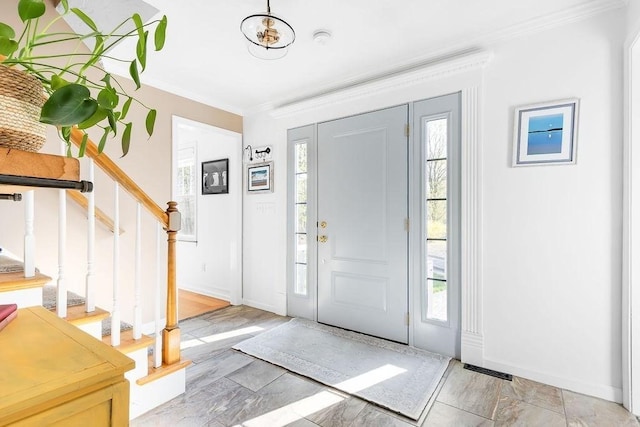 foyer entrance with crown molding, stairway, and a wealth of natural light