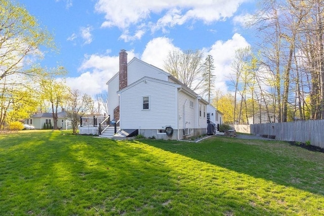 view of side of property with fence, a chimney, and a lawn