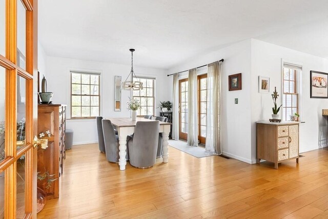 dining area featuring baseboards, light wood finished floors, and a notable chandelier