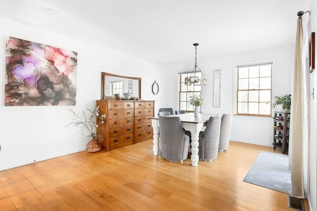 dining room featuring light wood-style floors, baseboards, and a notable chandelier