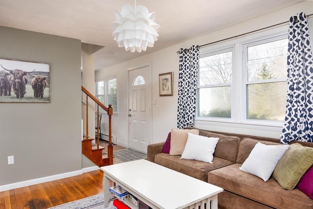 living area with a baseboard radiator, stairs, baseboards, and wood finished floors