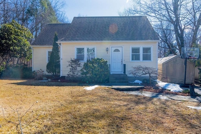 view of front of house featuring an outbuilding, roof with shingles, a front yard, and entry steps