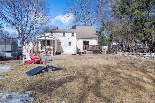 rear view of property with a yard, a trampoline, a deck, and a chimney