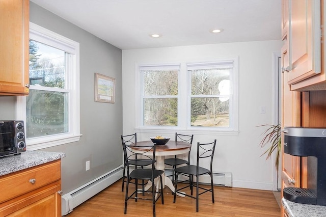 dining area featuring breakfast area, a baseboard radiator, baseboards, and light wood-style floors