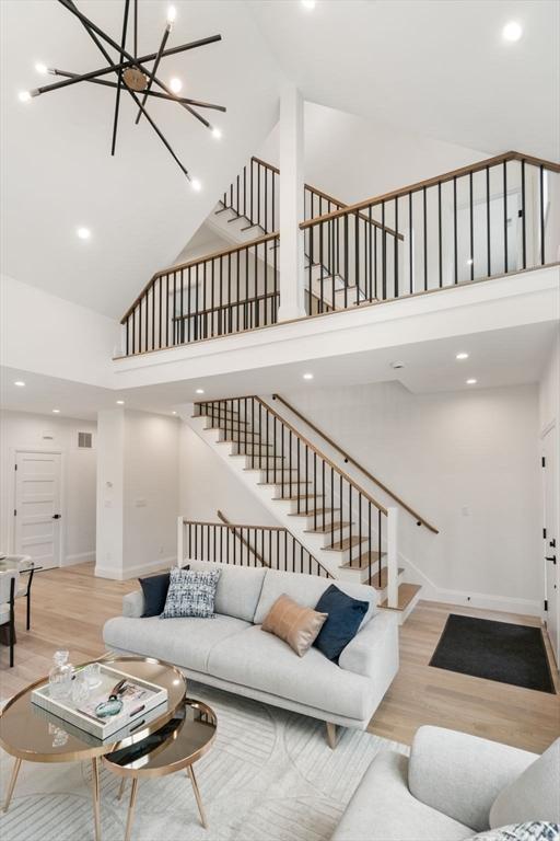 25 Johnson Pl Unit 25, Newton, MA 02466 - living room with high vaulted ceiling, stairway, wood finished floors, a chandelier, and recessed lighting