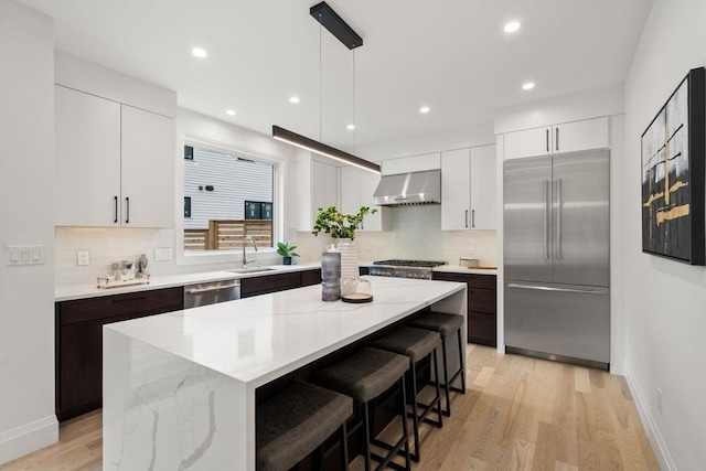 25 Johnson Pl Unit 25, Newton, MA 02466 - kitchen with stainless steel appliances, wall chimney range hood, light wood-type flooring, tasteful backsplash, and recessed lighting