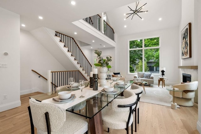 25 Johnson Pl Unit 25, Newton, MA 02466 - dining space featuring light wood-type flooring, recessed lighting, stairway, a towering ceiling, and a glass covered fireplace