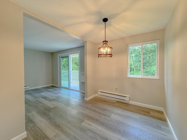 empty room featuring baseboards, baseboard heating, and wood finished floors